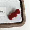 Primo piano sui dettagli della molletta per capelli ondulata in acetato rosso lucido e liscia. - Rosso-4cm