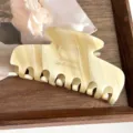Vista detallada de la elegante pinza para el cabello de acetato beige con diseño marmoleado. - Blanco Roto