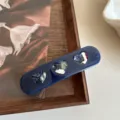 Primer plano de la pinza para el pelo de acetato azul oscuro con tres recortes de corazones. - 9cm / Azul marino