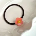 Vista detallada de una linda goma para el cabello con un dije de flor de color rosa. - Rosa