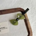Primer plano detallado de la pinza de pelo con lazo de resina verde sobre bandeja de madera. - 6.5CM / Verde
