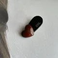 Primer plano detallado de una horquilla de pelo de corazón marrón oscuro con textura. - Corazón / Café