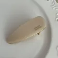 Primer plano de una pinza de acetato beige minimalista, superficie lisa e impresión dorada. - 6cm / Blanco Roto