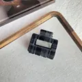Detalle de pinza de pelo de terciopelo a cuadros negros, superficie suave, accesorio elegante. - Estilo Cuadrado / Negro