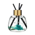 Glass reed diffuser bottle with dried flowers and black sticks for home fragrance decor. - Wild Bluebell
