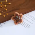 Close-up of handmade wool felt star with embroidery and beads for DIY hair accessories. - Brown Star Bread