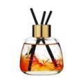 Reed diffuser variant with gold cap, clear glass bottle, and vibrant floral botanical inside. - Encounter