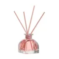Aromatherapy reed diffuser with pink scented oil in a clear glass bottle for home. - Peach