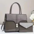 Detalle de bolso de charol gris con solapa efecto cocodrilo, cierre metálico. - Gris