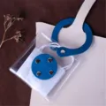 Detailed view of clear PVC mask storage bag with blue leather strap and snap button close. - Blue