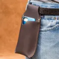 Vista dettagliata della custodia per telefono in pelle marrone scuro indossata in cintura. - Marrone