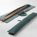 Dark green leather drumstick roll bag with secure strap and wooden drumsticks inside. - Green