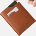Leather passport holder detail shot showing card slot and brown texture finish. - Brown
