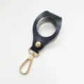 Black leather golf ball holder keychain detail view, gold metal clasp and snap button. - Black