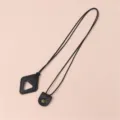 Close up detail of black leather sunglasses strap lanyard with triangle pendant and metal snap. - Black