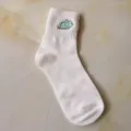 Close-up detail of white mid-calf cotton sock featuring cute embroidered blue dinosaur motif. - One Size / White
