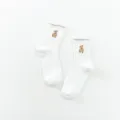 White ribbed crew socks for women featuring cute brown teddy bear embroidery and soft fabric. - White