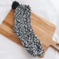 Close-up of fuzzy coral fleece winter thermal warm sleep sock with black pom-pom detail. - Mixed Black White Gray