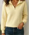 Close-up view of the waffle knit half-zip long sleeve sweatshirt texture and collar detail. - Yellow