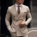Gros plan détaillé d'une veste de costume croisée beige pour homme avec cravate et pochette. - S / Haut et Bas / Beige