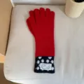 Vue detaillee des gants tricot longs rouges et noirs a pois avec une etiquette tissee. - Taille unique / Rouge