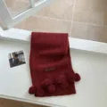 Vue détaillée de l'écharpe en tricot rouge foncé avec des pompons mignons et une texture douce. - Style Pompon / Rouge