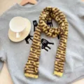 Vue détaillée de l'écharpe en tricot rayé avec une texture douce et un design jaune-brun chaleureux. - Baguette à Pois / Largeur 9cm / Jaune Café
