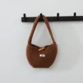 Vue de détail rapprochée du sac cabas en tricot marron montrant la texture et le bouton. - Couleur caramel