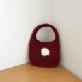 Sac à main en tricot rouge avec décoration pompon mouton pelucheux gros plan détail. - Cuivre Rétro
