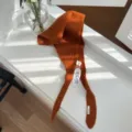 Vue rapprochée détaillée montrant la texture du tissu foulard triangulaire en tricot orange - Rouge Orangé