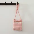 Détail de mini sac bandoulière en tricot rayé rose et blanc accroché au crochet. - Rose et Beige