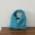 Vue détaillée d'un sac à main tricoté en mohair bleu douillet avec un bouton en corne. - Bleu lac
