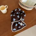 Brown knit scarf featuring blue heart patterns and white scalloped edge details closeup. - Overlock Heart / Coffee