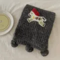 Detailed view of dark gray knitted winter scarf with cute little horse embroidery and fluffy pom poms. - 18x160cm / Dark Gray