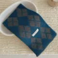 Gros plan sur une douce echarpe en tricot argyle bleu gris avec une etiquette effet laine. - Gris Bleu / Écharpe Croisée Argyle