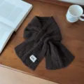 Vue détaillée de l'écharpe croisée en tricot de laine marron foncé, texture douce et chaleureuse. - Design Croisé Torsadé / Café