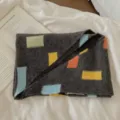 Gros-plan d'une écharpe en tricot gris foncé avec des blocs colorés, style automne et hiver. - Gris foncé