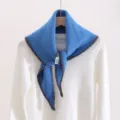 Blue knitted triangular scarf detail showing the unique brown edge stitching and soft texture. - Geometric Blue / Blue