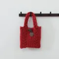 Détail de sac cabas en tricot torsadé rouge, vue de poignée de sac à main d'hiver - Style Torsades Bouton / Cuivre Rétro