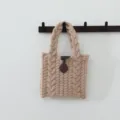 Vue détaillée d'un sac à main en tricot torsadé beige douillet avec fermeture à genouillère. - Style Torsades Bouton / Kaki