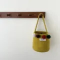 Vue détaillée d'un sac seau en feutre jaune-vert stylé avec de charmants pompons colorés. - Jaune Citron