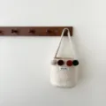 Détail de sac seau en feutre crème, avec pompons colorés et étiquette de marque cousue. - Blanc Laiteux