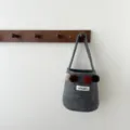Gros-plan sac seau en feutre gris avec pompons colorés suspendu patère en bois, chic. - Gris