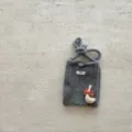 Vue détaillée du mini sac de téléphone en tricot gris avec charm oie et étiquette. - Sac à Téléphone Oie / Gris