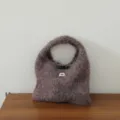 Gros plan détail du sac à main tricoté en mohair pelucheux avec bouton et étiquette. - Gris Violet