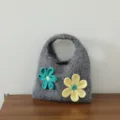 Gros plan détaillé du sac à main tricoté gris avec fleurs au crochet 3D et fermeture à bascule. - Bouton Olive Fleur / Gris Premium