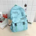 Stylish light blue canvas backpack with cute bear pendant, ideal for students and daily commuting. - Charm / Green