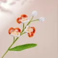 Primo piano di ramo di orchidea all'uncinetto fatto a mano, con trama di filato fine e dettagli precisi. - Arancione