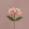 Dettaglio fiore non-ti-scordar-di-me all'uncinetto fatto a mano, trama lana e toni pastello. - Sfumatura rosa