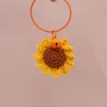 Dettaglio di ciondolo girasole all'uncinetto fatto a mano, petagli gialli e campanella arancione. - Ciondoli a Girasole
